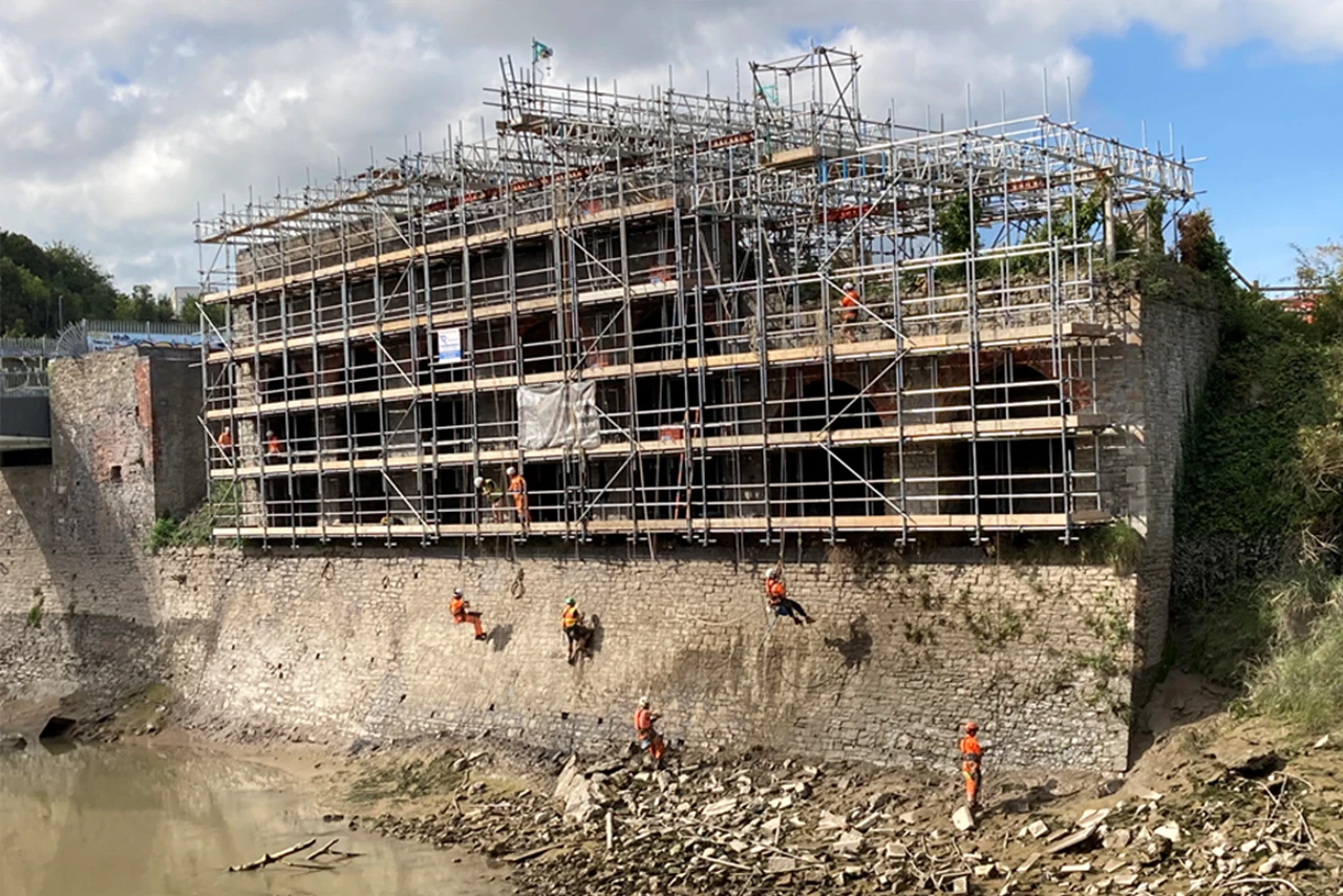 Historic river walls at Temple Island with scaffolding and workers repairing.